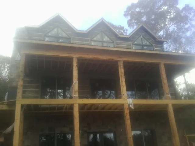 Dormers and porch framing on a large log home under construction — Roof Coating work by our crew in Locust Grove
