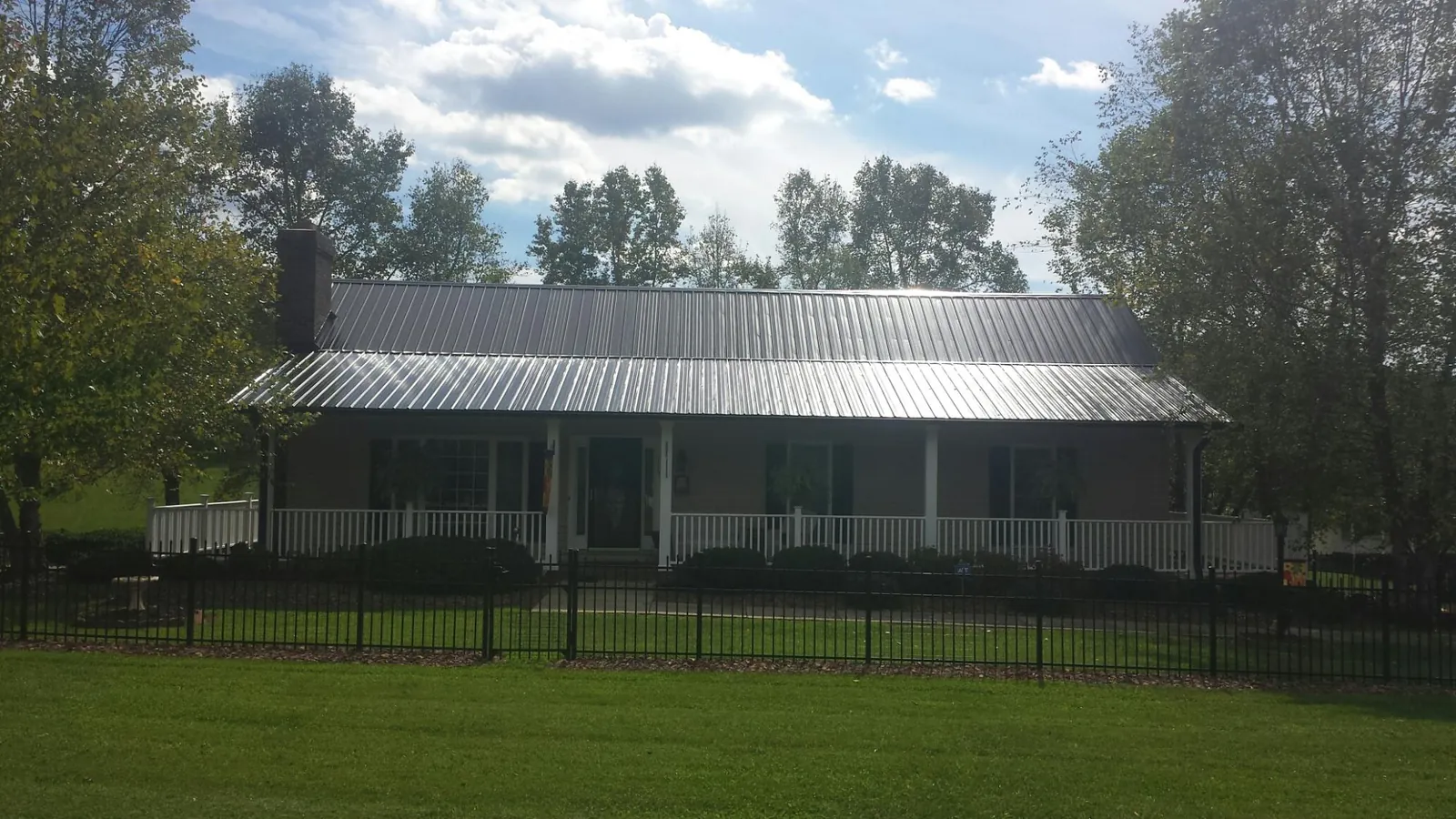 Gray metal roof on a brick ranch with a full width front porch — Gutter Guard Installation work by our crew in Locust Grove