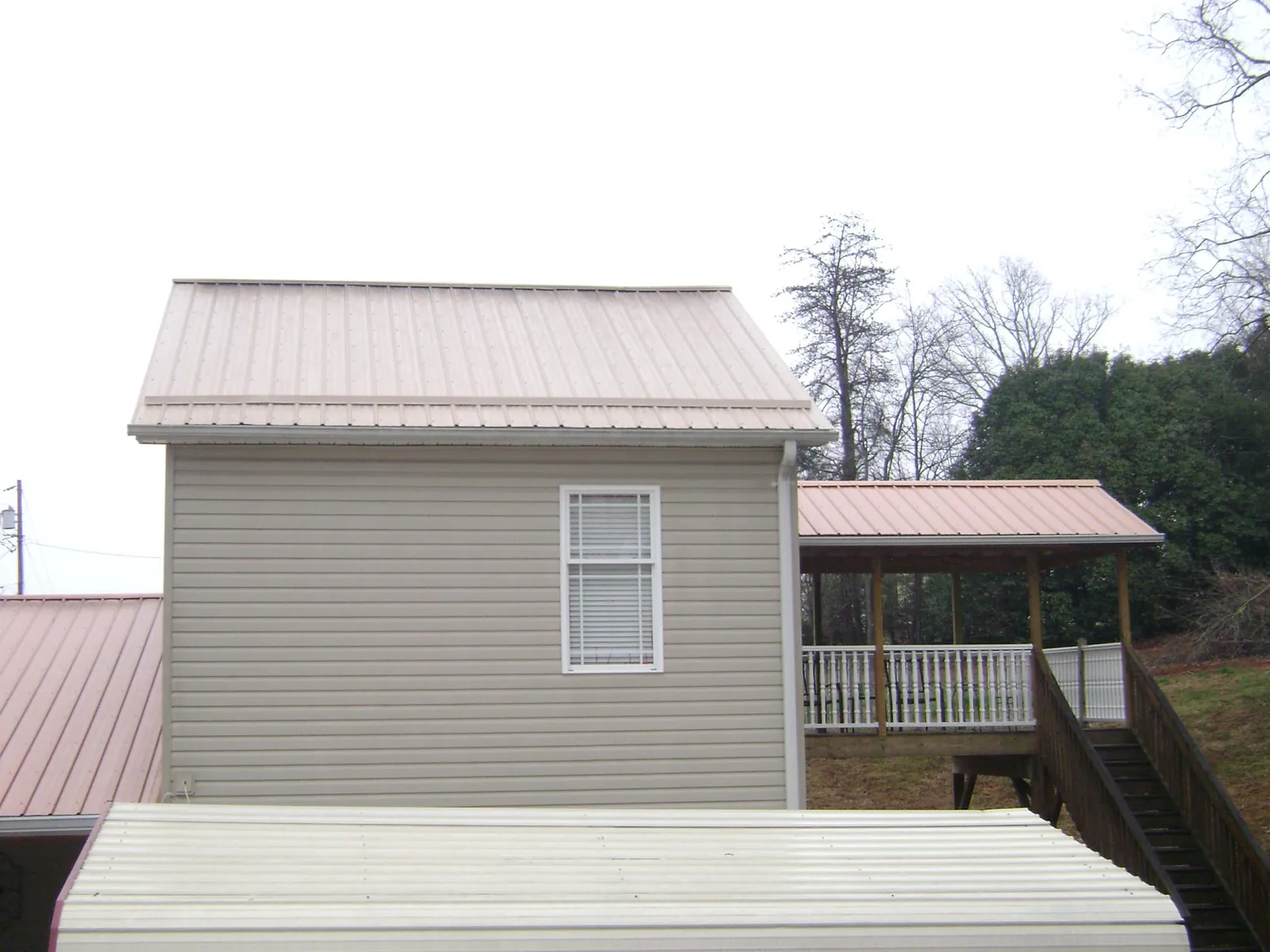 Tan metal roofs on a two story addition and attached porch in Locust Grove