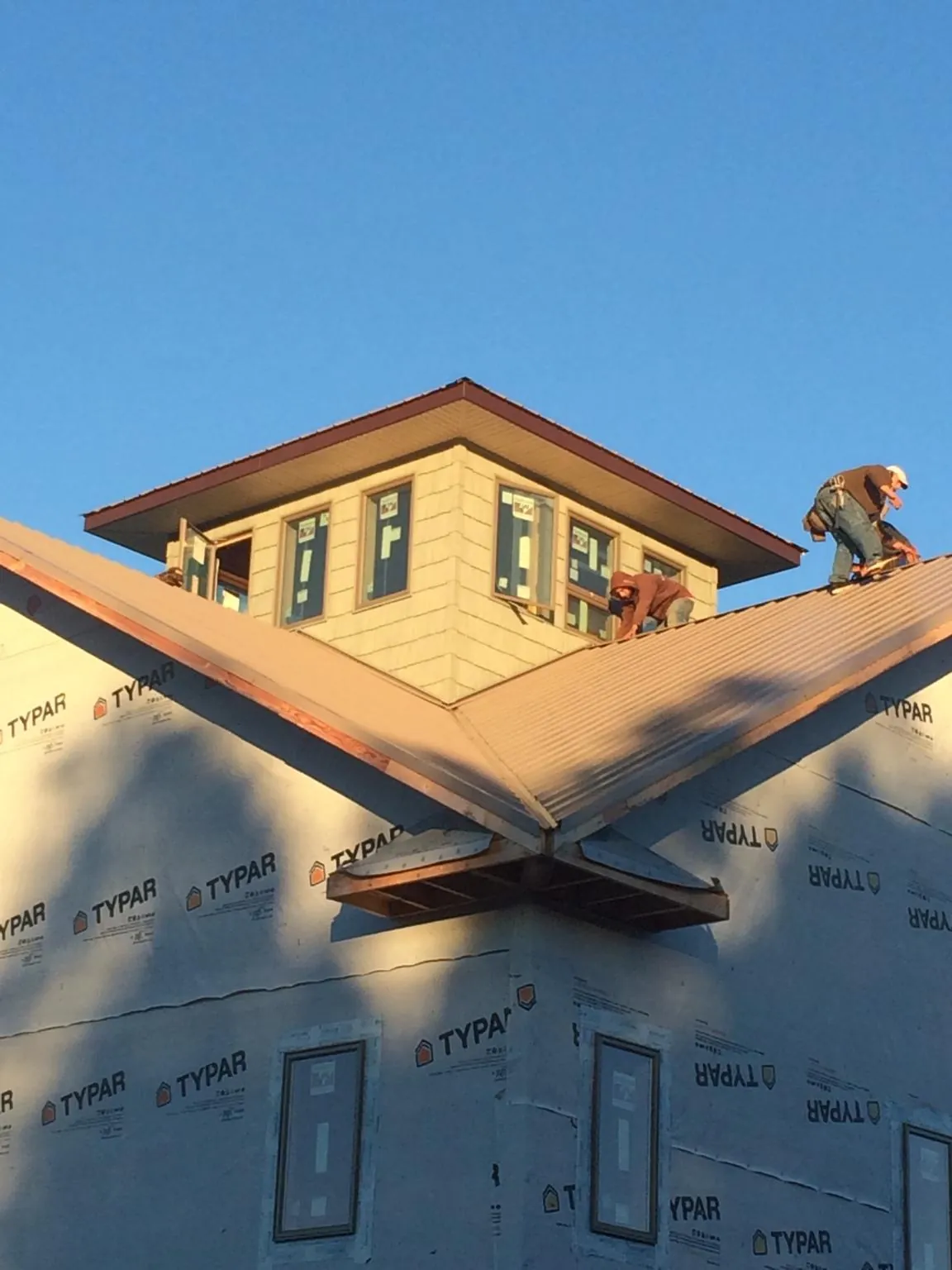 Roofers working around a rooftop cupola on a new metal roof at sunset — Roof Waterproofing in Locust Grove by Roofing Brothers